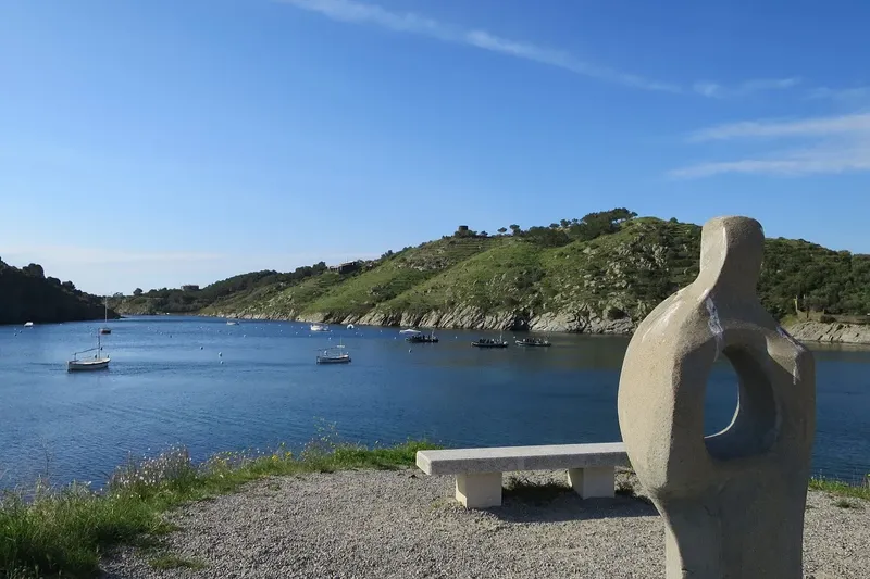 Vue sur une crique avec des bateaux amarrés et une sculpture