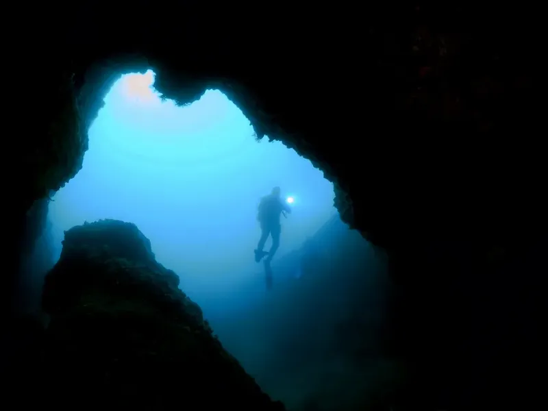Plongeur éclairé par une lampe dans une grotte sous-marine