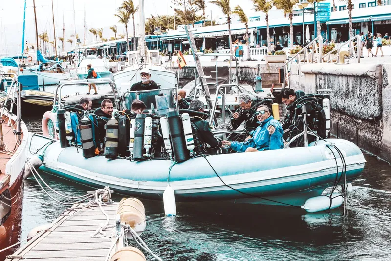Plongeurs équipés à bord d'un bateau pneumatique dans un port ensoleillé