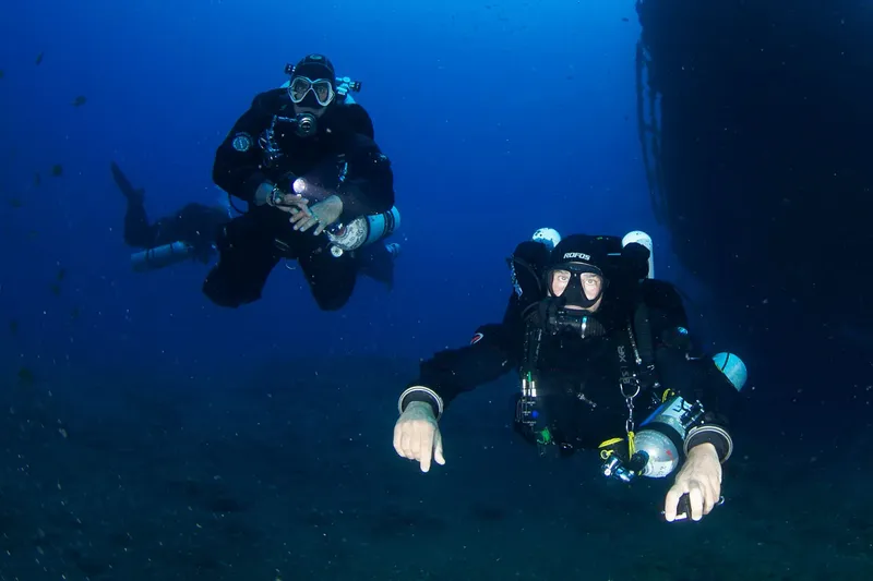 Deux plongeurs en combinaison explorent les profondeurs bleues sous-marines