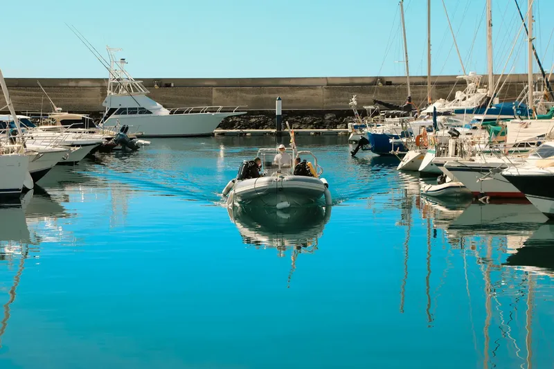 Un bateau semi-rigide navigue dans un port ensoleillé avec des passagers