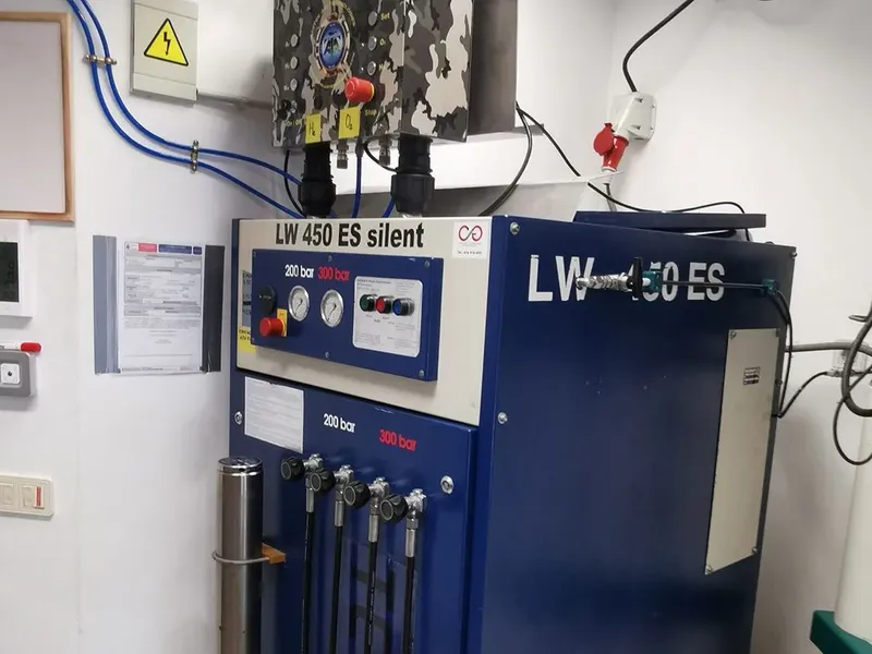 Compresseur de plongée bleu et gris avec manomètres et tuyaux connectés