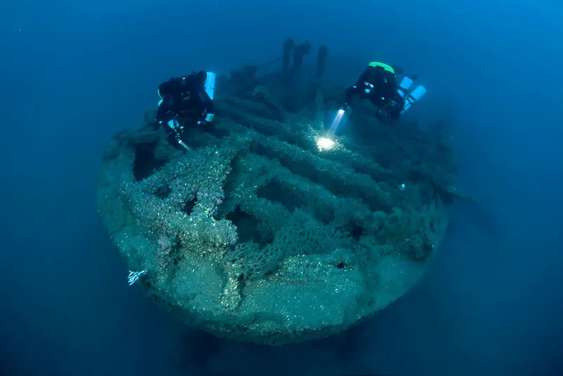 Deux plongeurs explorent l'épave d'un navire colonisé par la vie marine