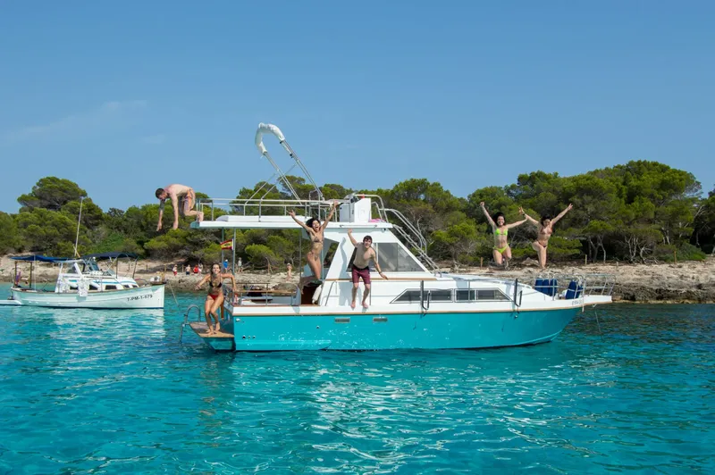 Groupe de personnes s'amusant et sautant d'un bateau en mer turquoise