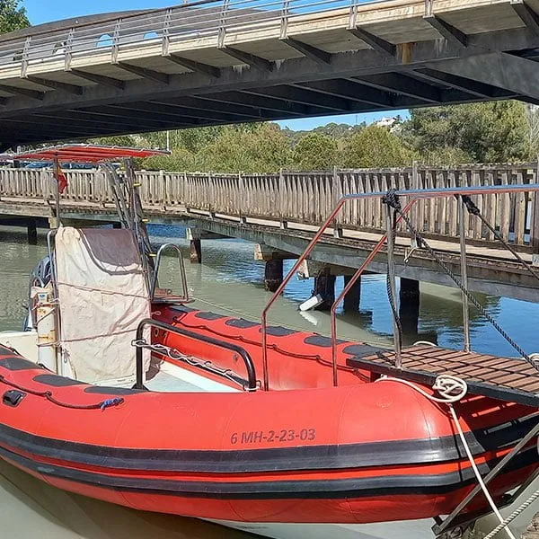 Bateau pneumatique rouge amarré à un ponton en bois au soleil