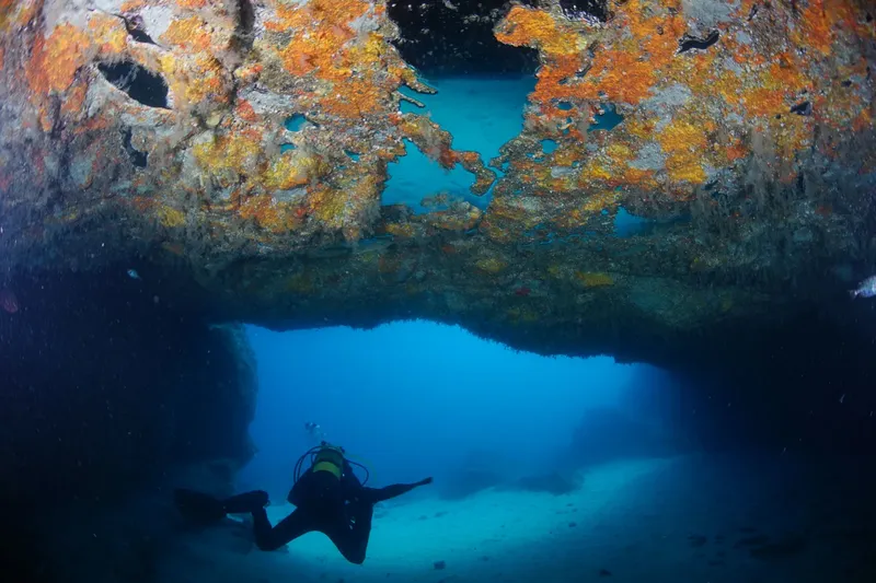 Plongeur explorant une grotte sous-marine avec une lumière bleutée