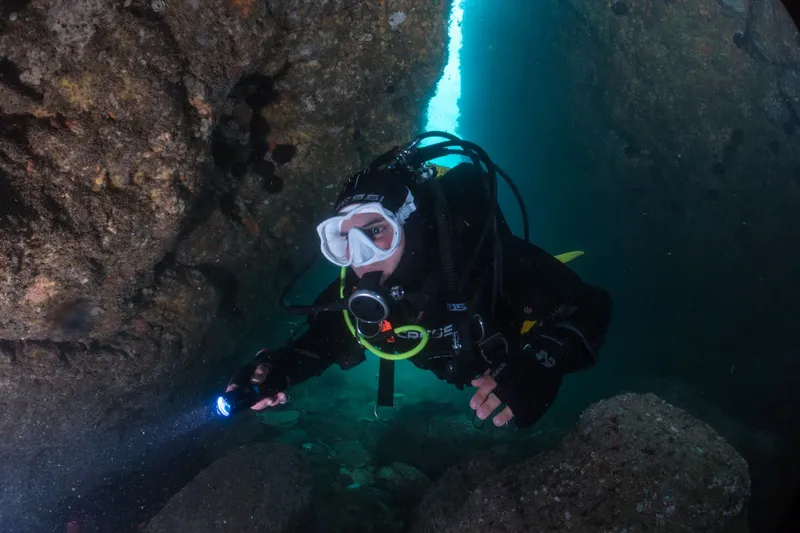 Plongeur explore une grotte sous-marine avec une lampe torche