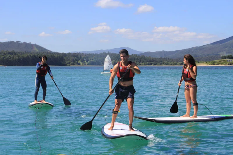 Trois personnes pratiquent le stand-up paddle sur une eau turquoise