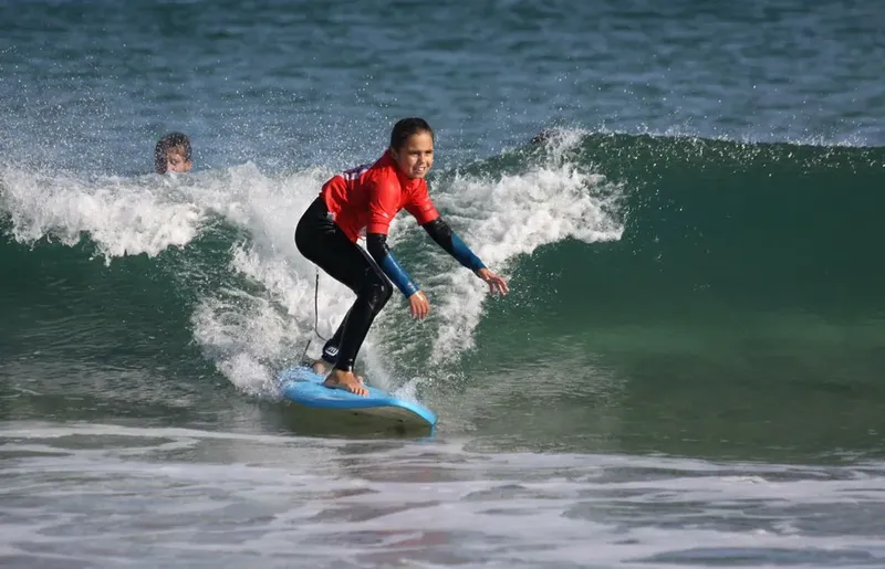 Jeune surfeur sur une vague, en pleine action, océan bleu