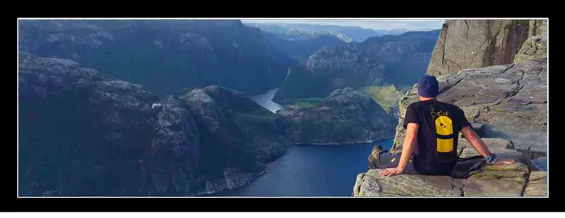 Plongeur assis sur un rocher surplombant un fjord norvégien bleu