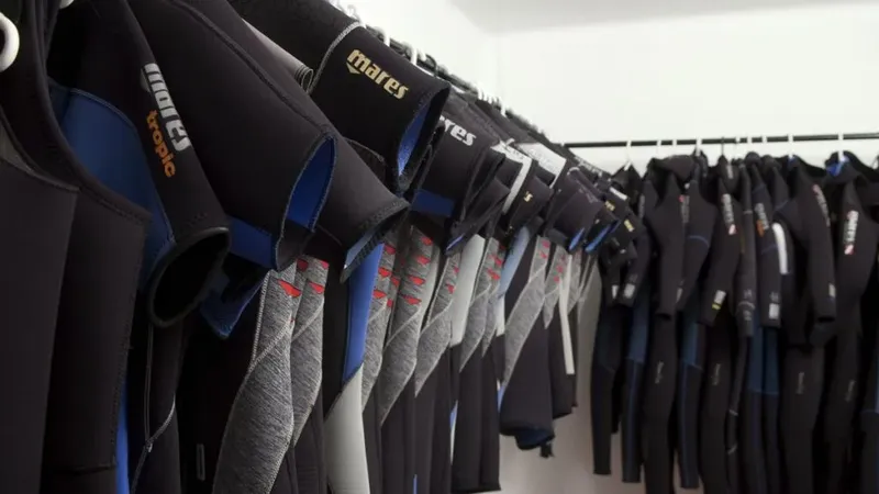Rangée de combinaisons de plongée noires et bleues suspendues sur cintres