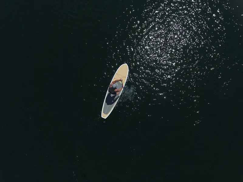 Personne pratiquant le stand-up paddle sur une eau scintillante