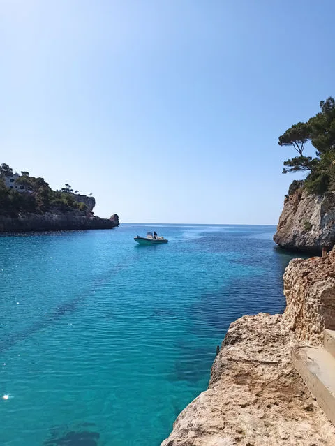 Une petite embarcation navigue sur une mer turquoise entre des falaises