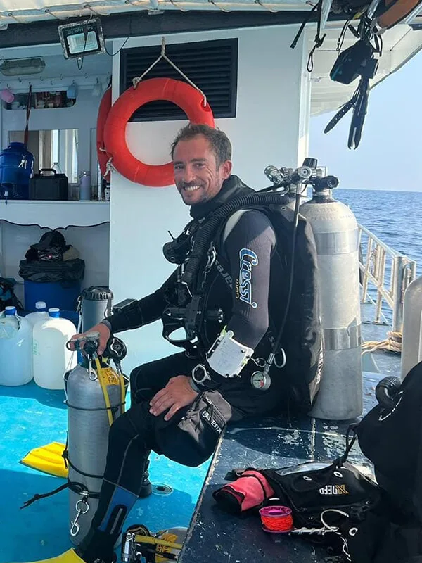 Plongeur souriant assis sur le bateau avec son équipement complet