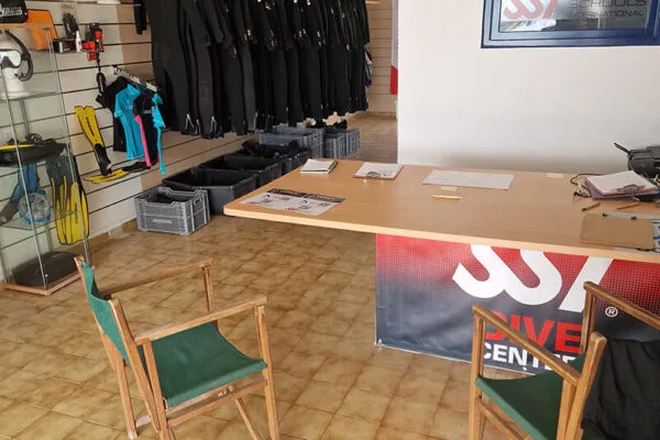 Intérieur d'un centre de plongée avec matériel, comptoir et combinaisons