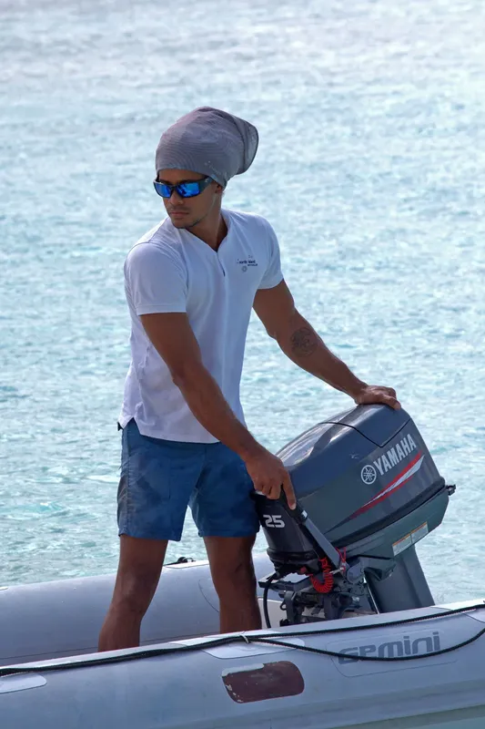 Un homme ajuste le moteur hors-bord d'un bateau pneumatique blanc
