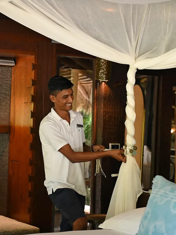 Un homme arrange un rideau de lit dans une chambre décorée