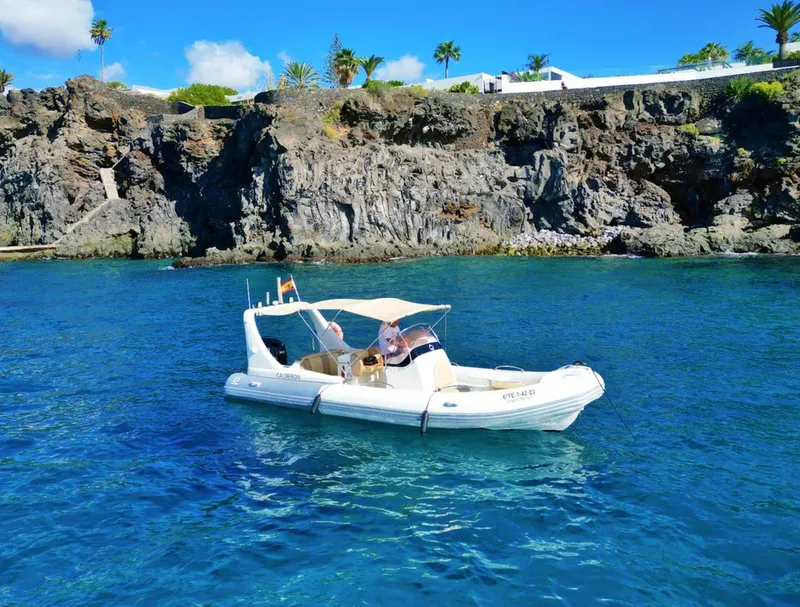 Petit bateau pneumatique blanc navigue sur une mer bleue claire