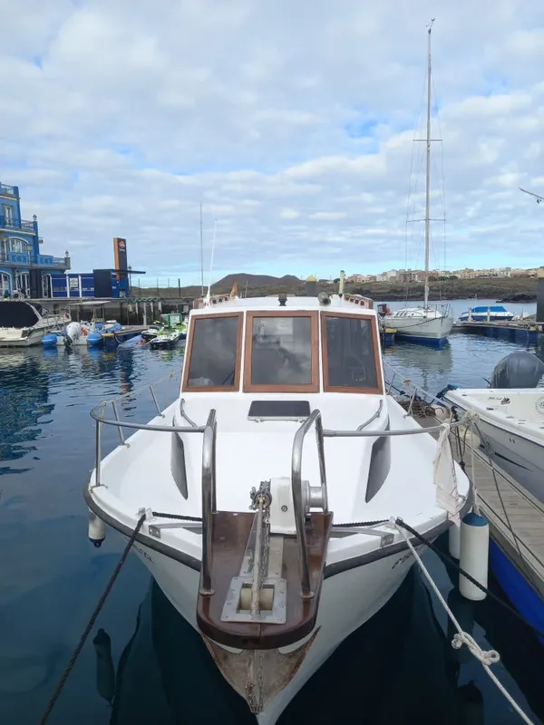 Bateau de plongée amarré dans un port ensoleillé avec d'autres embarcations