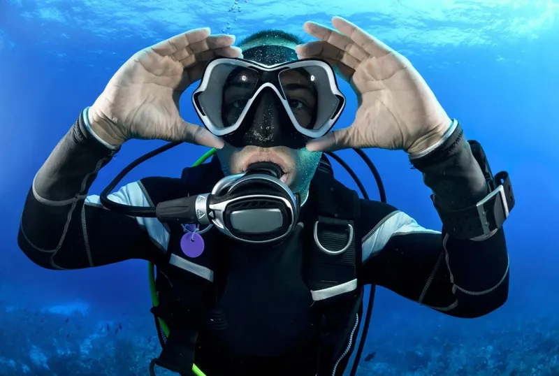 Plongeur souriant avec masque et détendeur sous l'eau bleue