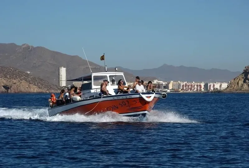 Bateau orange et bleu en mer avec des passagers à bord