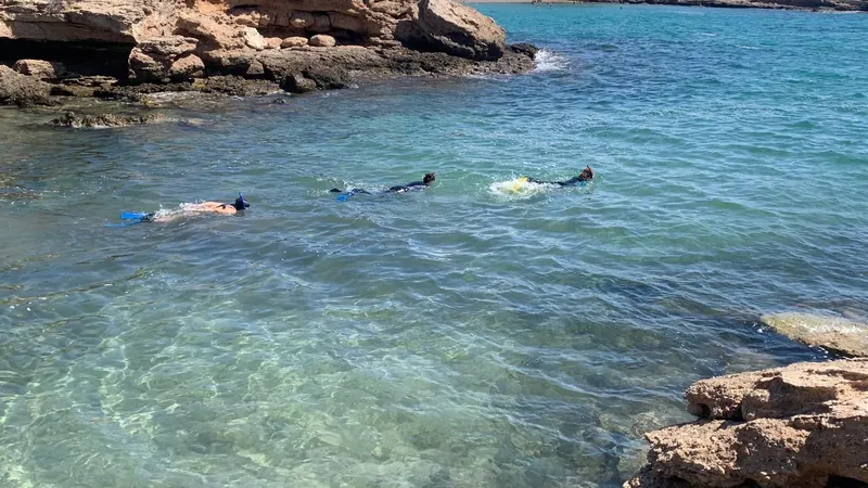 Trois personnes pratiquent le snorkeling dans une eau claire et turquoise