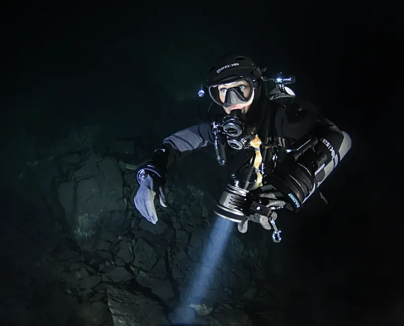 Plongeur en grotte sous-marine, éclairé par une lampe torche puissante