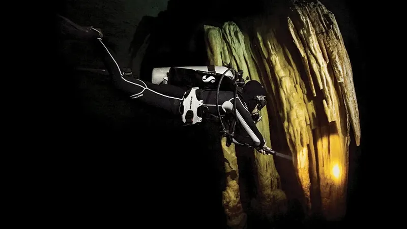 Plongeur explore une grotte sous-marine éclairée, ambiance mystérieuse et sombre