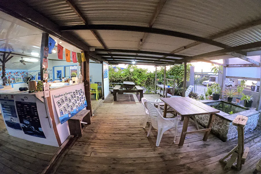 Terrasse couverte d'un centre de plongée avec tables et végétation tropicale