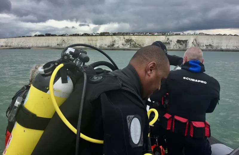 Deux plongeurs s'équipent sur un bateau semi-rigide par temps nuageux