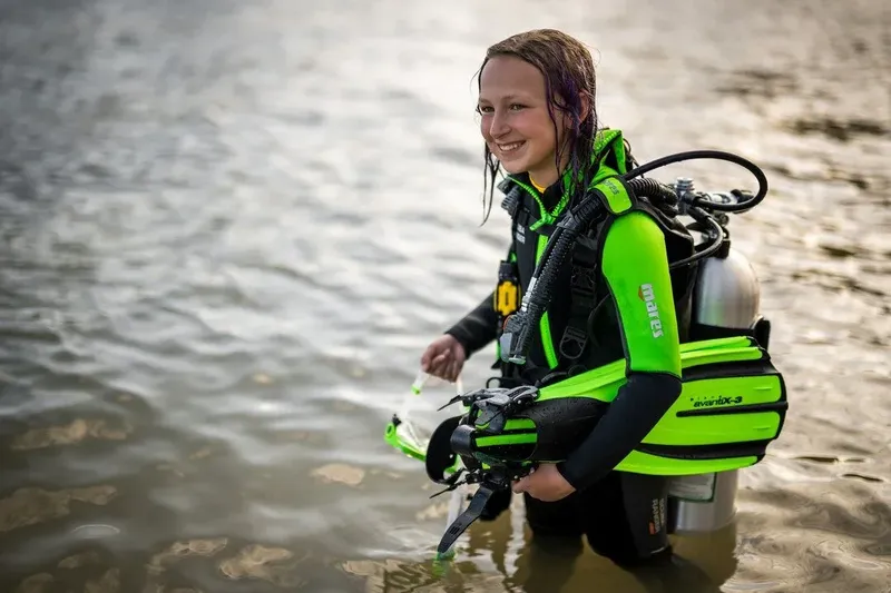 Jeune femme souriante en combinaison de plongée dans l'eau peu profonde