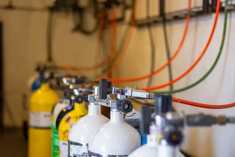 Bouteilles de plongée alignées avec raccordements et tuyaux colorés