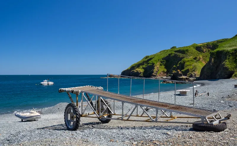 Plage de galets, rampe d'accès à la mer et bateaux au loin