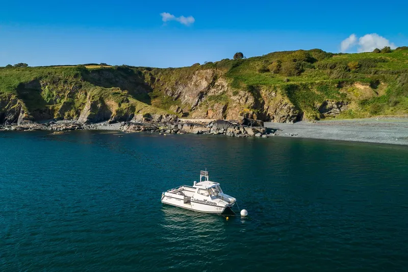 Bateau de plongée amarré dans une crique rocheuse sous un ciel bleu
