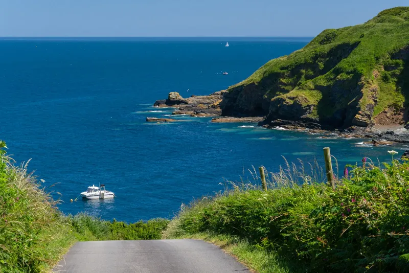 Vue d'une côte rocheuse avec un bateau en mer et une route