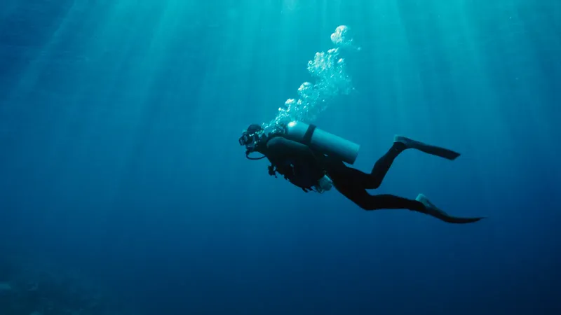 Plongeur en combinaison nageant dans une eau bleue et lumineuse