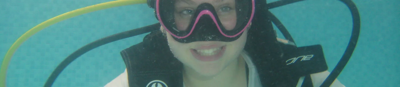 Plongeuse souriante avec masque et gilet, prise de vue sous-marine