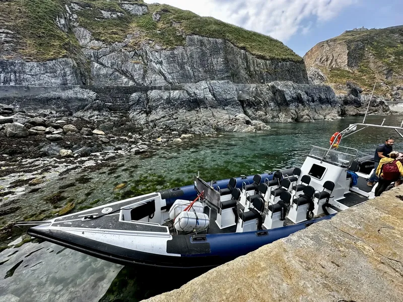 Bateau semi-rigide amarré dans une crique rocheuse avec des plongeurs
