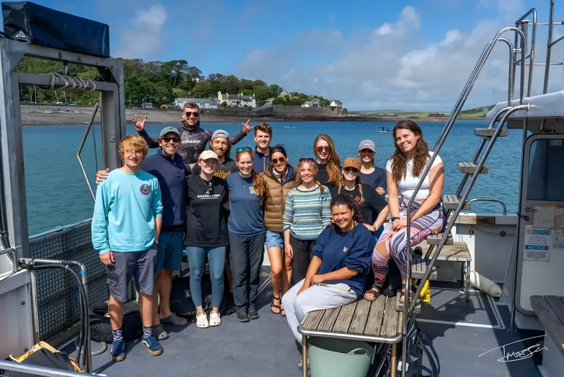 Groupe de personnes souriantes sur un bateau en mer, journée ensoleillée