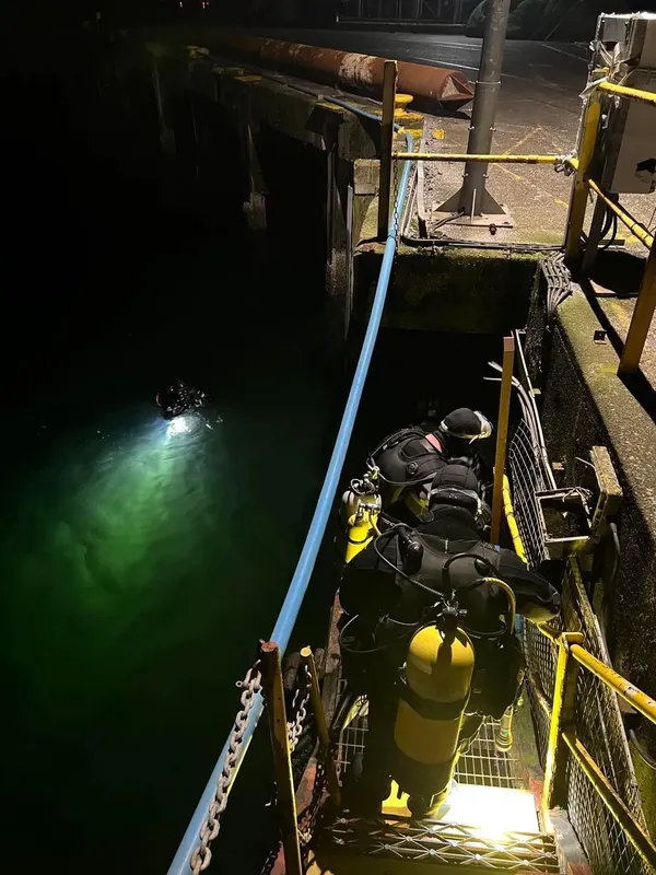 Plongeur s'équipant au bord d'un quai, préparation immersion nocturne