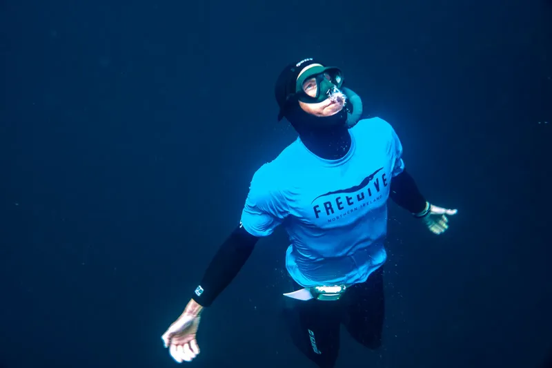 Apnéiste en immersion, regardant vers le haut dans l'eau bleue