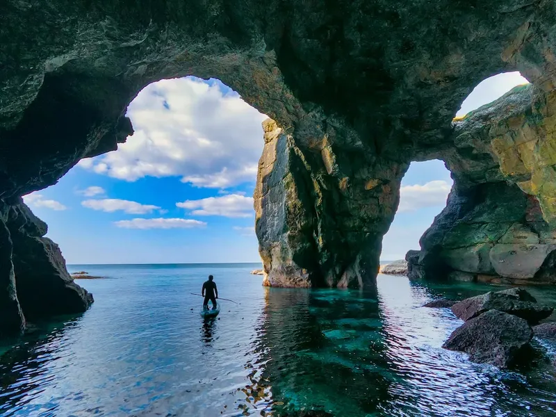 Une personne debout sur une planche dans une grotte marine