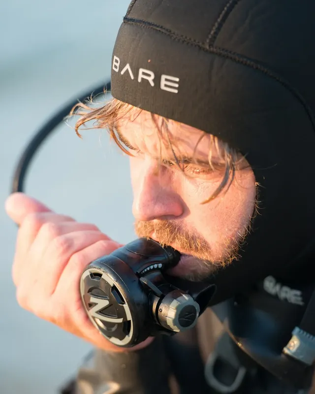 Plongeur vérifiant son détendeur avant immersion en mer