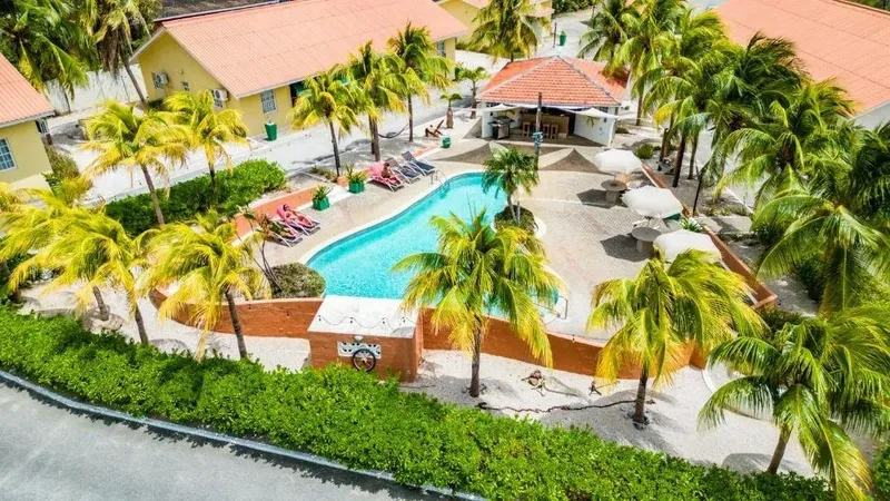 Vue aérienne d'une piscine entourée de bâtiments et de végétation tropicale