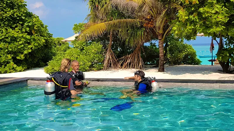 Trois plongeurs équipés discutent dans une piscine turquoise ensoleillée