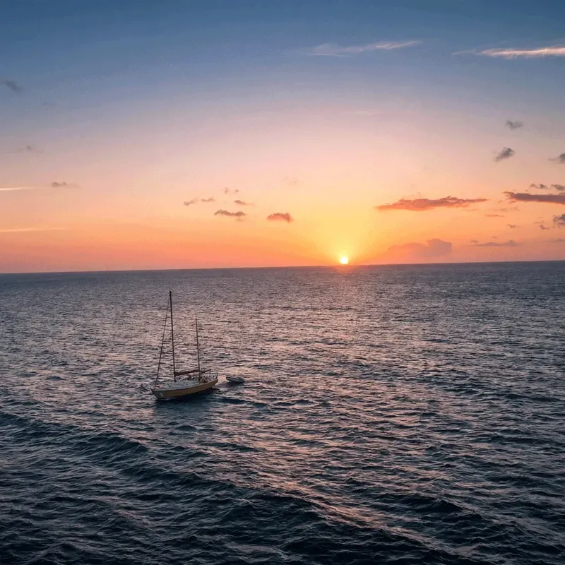 Voilier sur une mer calme au coucher du soleil orangé