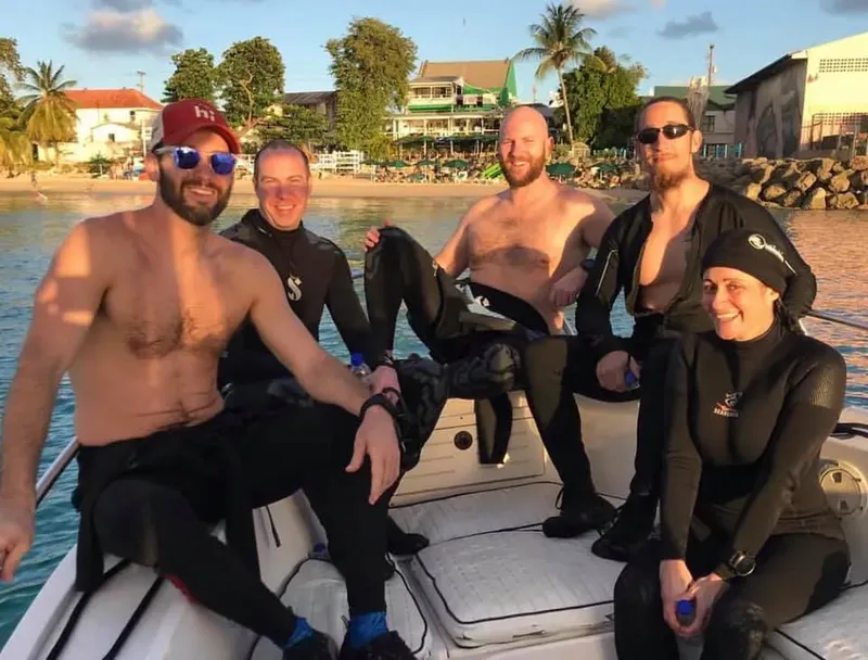 Groupe de plongeurs souriants assis sur un bateau pneumatique en mer