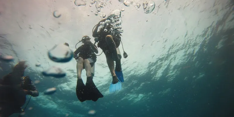 Deux plongeurs explorent les fonds marins, bulles et lumière diffuse