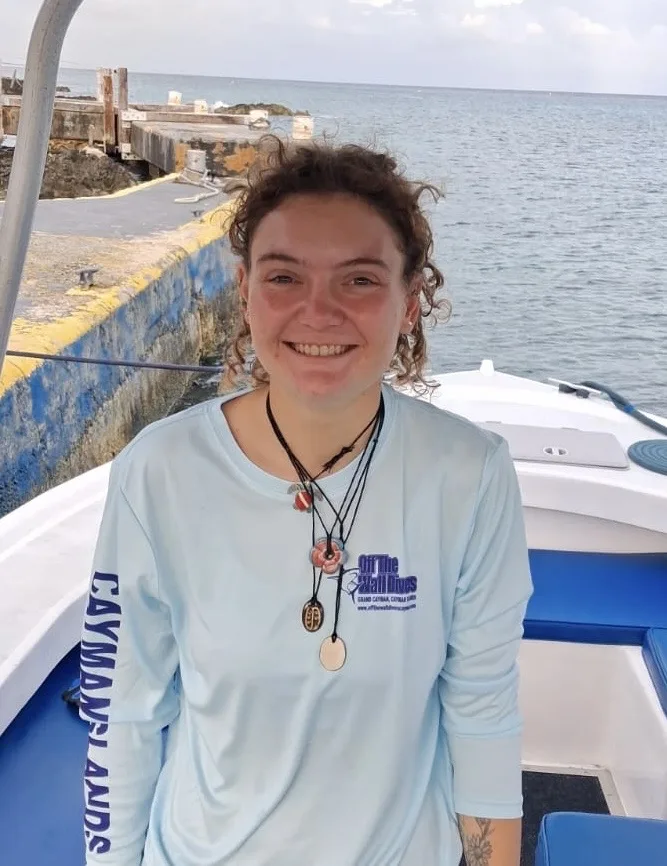 Jeune femme souriante sur un bateau en mer, portant un t-shirt