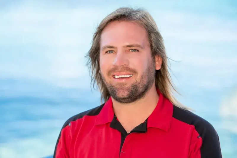 Portrait d'un homme souriant avec de longs cheveux blonds